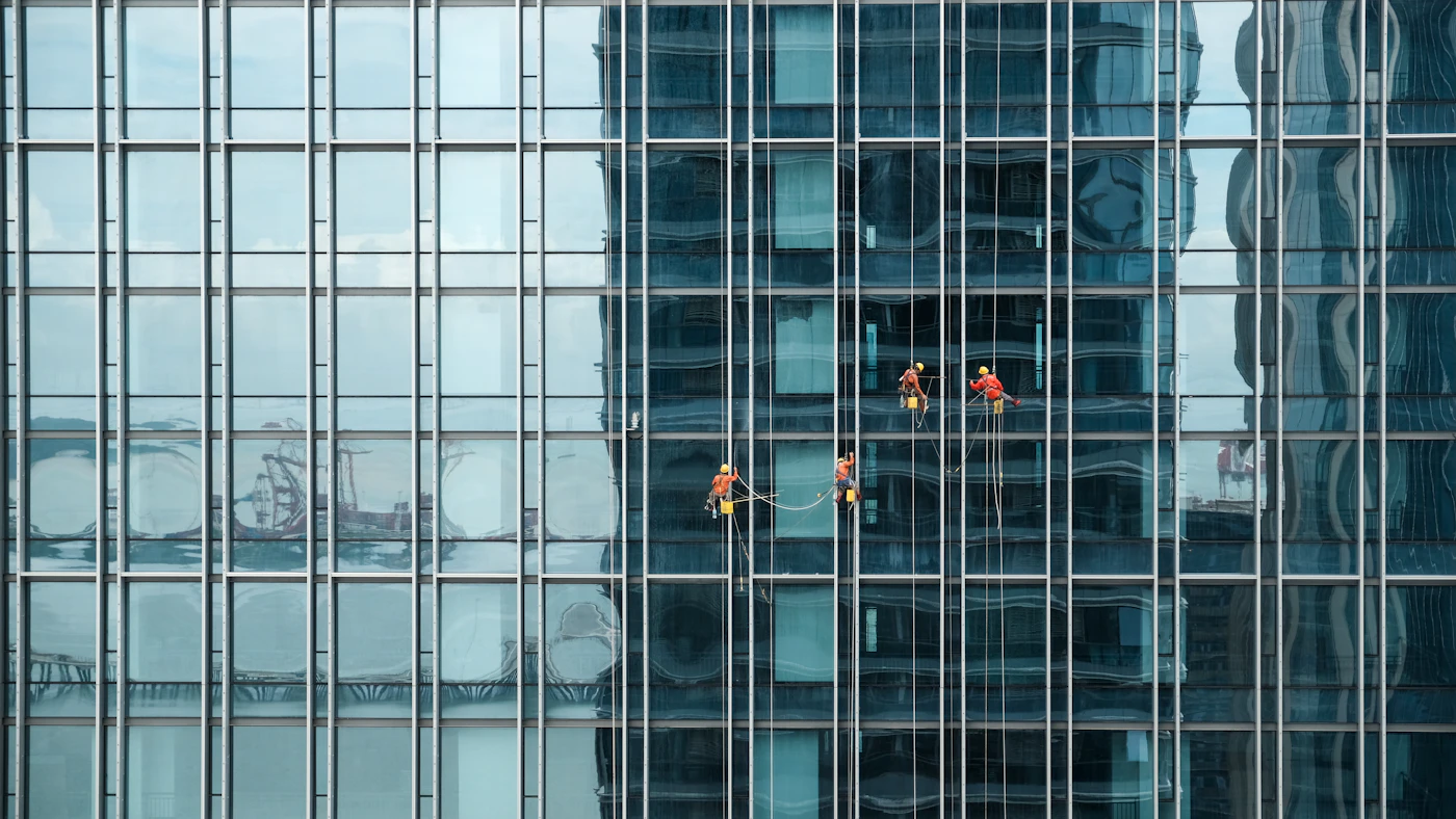 Rope-access technicians working down the glass face of a tower
