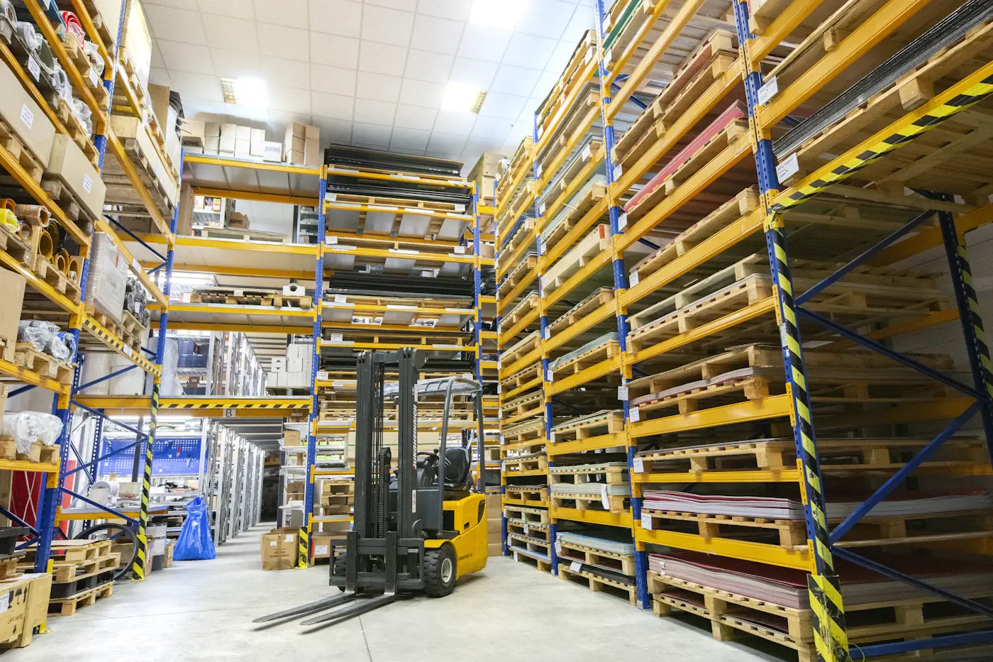 A forklift parked in an aisle of full-height pallet racking
