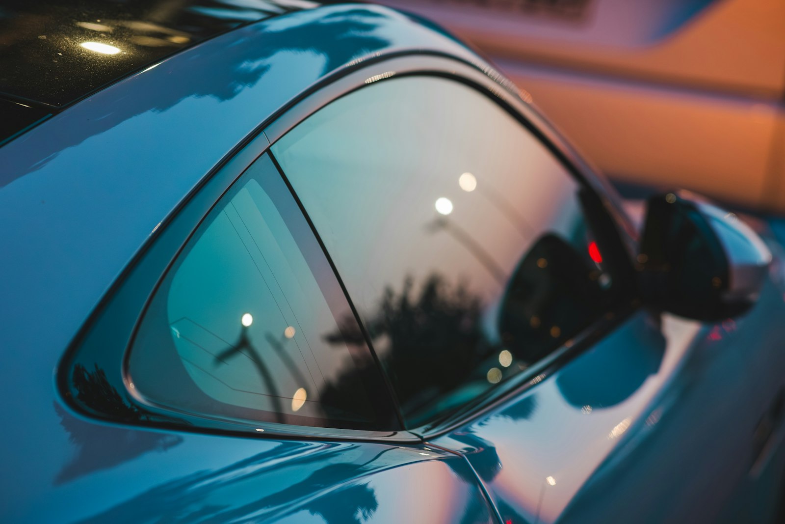 Evening light reflecting off the tinted quarter glass of a coupe